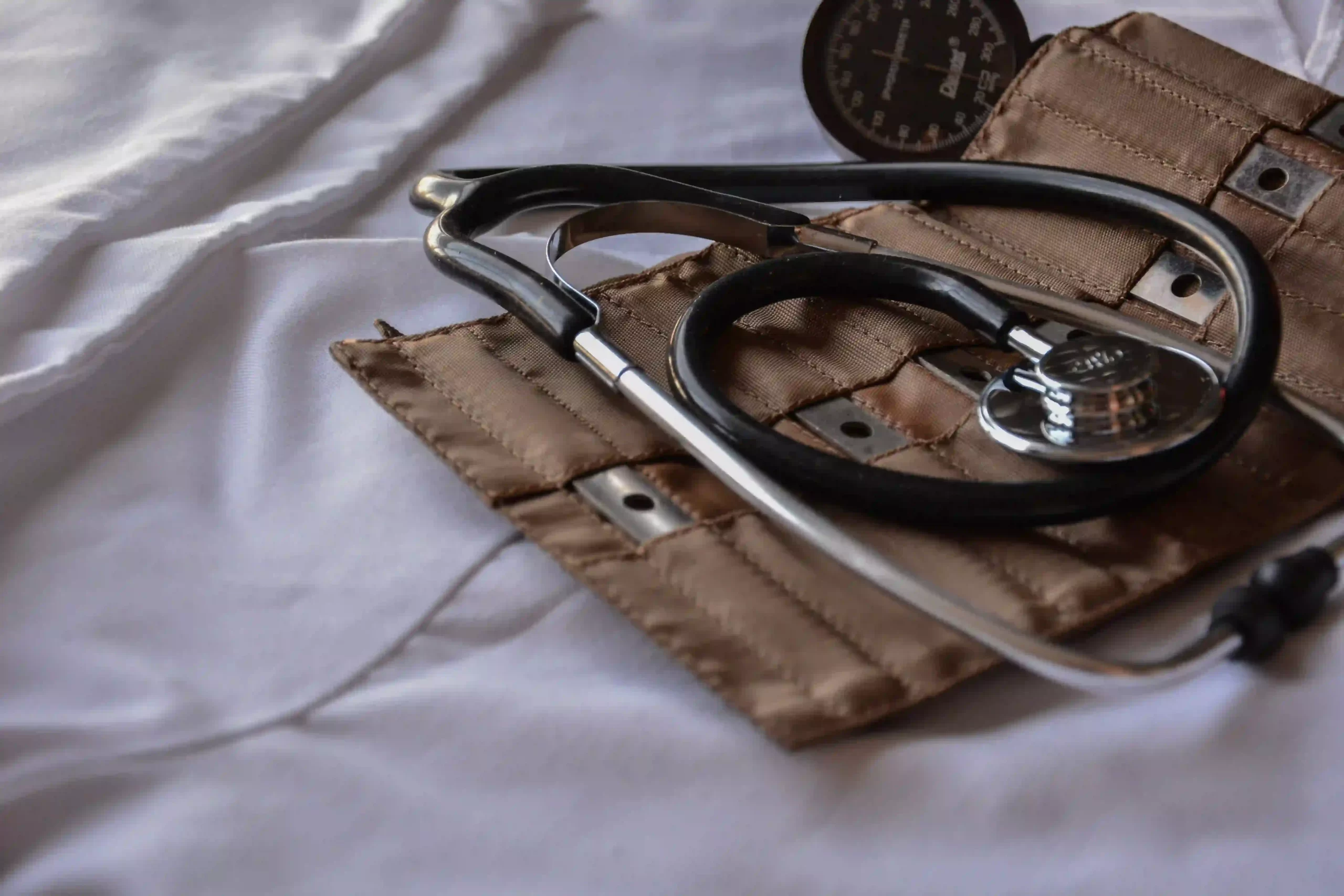 Stethoscope and baumanometer placed over white blankets